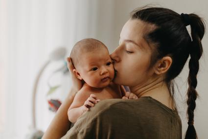 mothers with braid kissing newborn