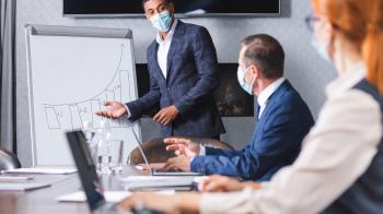 Mask wearing man leading a meeting