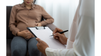 Pregnant patient with doctor writing on clipboard